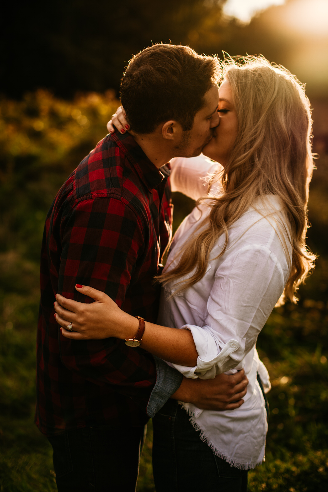 engaged couple kissing in a field emotional